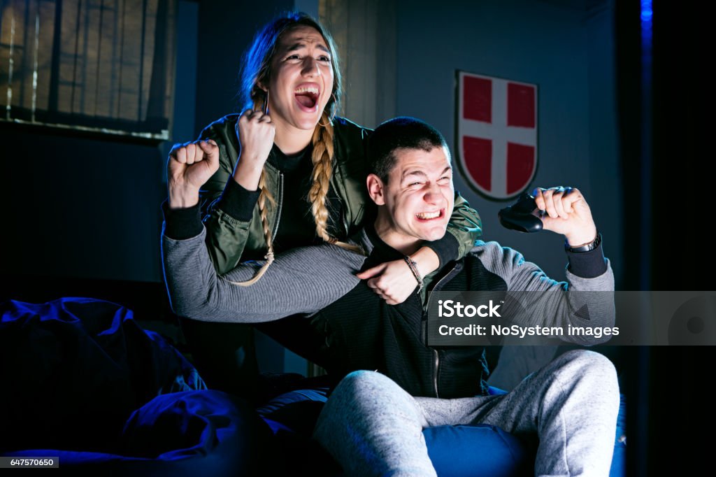 Happy couple playing video games and having fun together. Happy couple playing video games and having fun together. Studio shoot, indoors, colored flash light used. Boyfriend Stock Photo