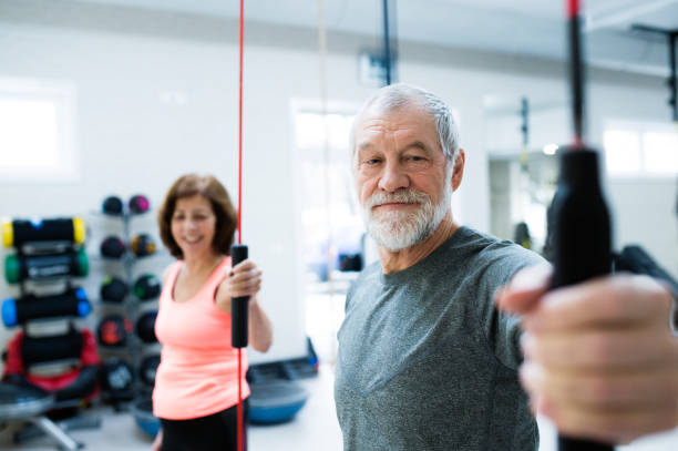 istock Senior couple in gym working out with vibration bars 647574128