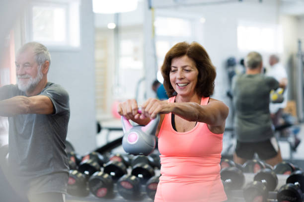 Senior couple in gym working out using kettlebells. Beautiful fit senior couple in gym working out using kettlebells. Sport, fitness and healthy lifestyle concept. kettlebell stock pictures, royalty-free photos & images