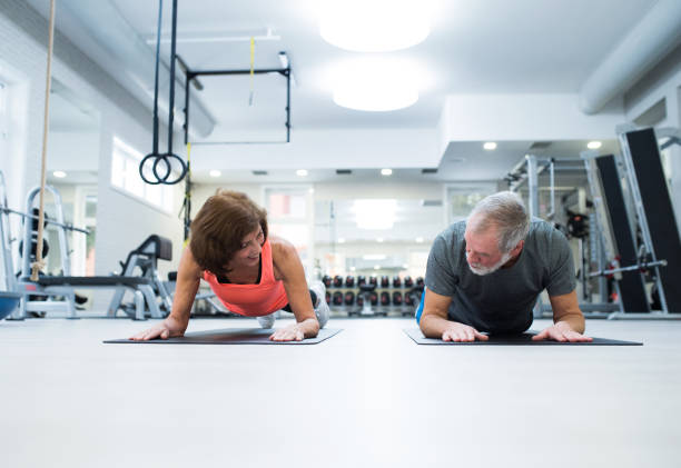 istock Senior couple in gym in plank position working abs 647577208