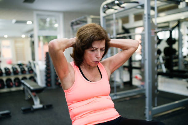 Side view of fit young woman doing pilates, working on abdominal muscles. Fitness woman exercising to improve core muscle strength in gym.