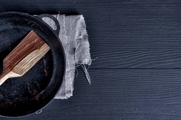 istock Frying pan with wooden spatula on a black surface 647578180