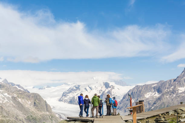 a group of people admire the jungfrau-aletsch glacier in front of them. - european alps switzerland glacier high angle view imagens e fotografias de stock