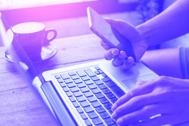 istock Hands holding mobile phone and working on computer typing laptop keyboard using wifi cyber internet online for business communication 647585936