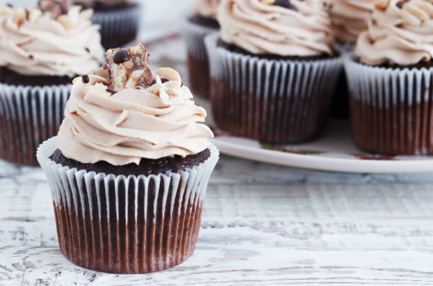 istock Chocolate cupcake with mousse cream icing on grunge white wooden background copy space 647592502