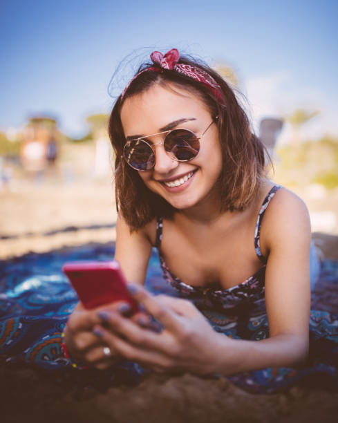 istock Young attractive woman texting on her smartphone at the beach 647603298