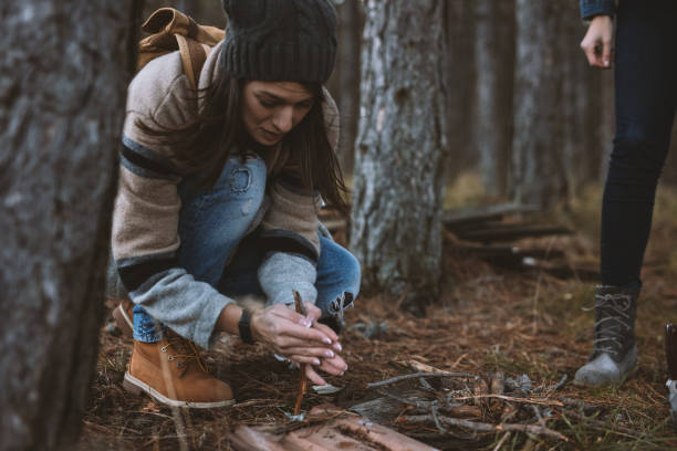 istock Young female camper is lighting fire primitive way with two sticks 647604328