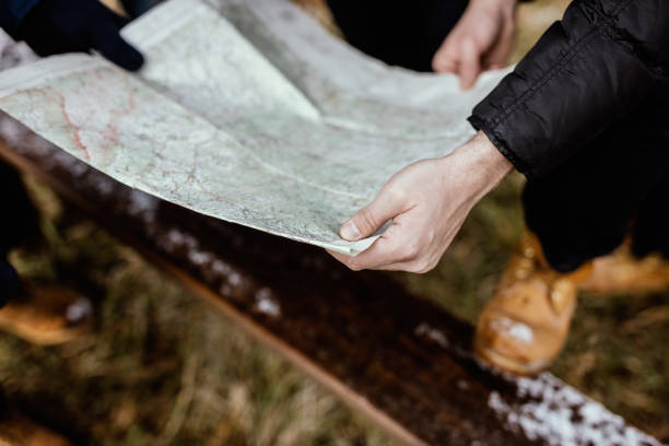 istock Lost group of adventurers checking map to find directions in wilderness 647618360