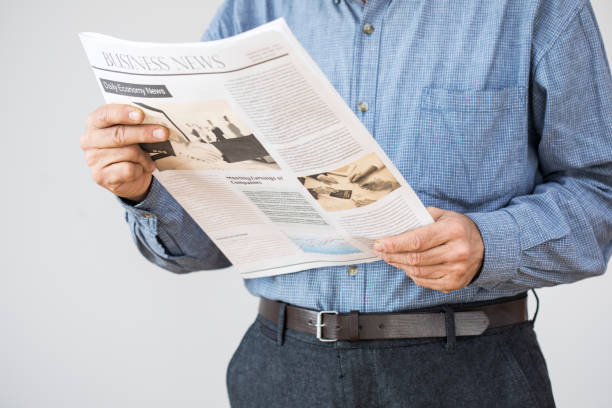 istock Man holding reading newspaper on gray background 647618870