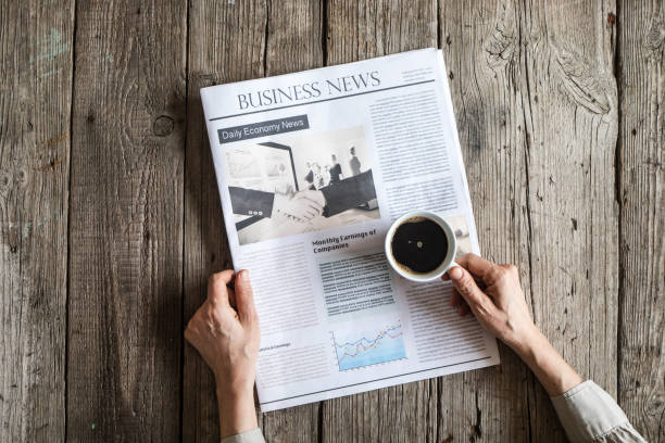 istock Woman reading newspaper on wooden table 647619448