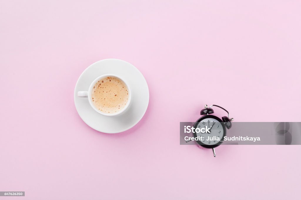 Alarm clock and morning coffee. Time to rest. Flat lay. Morning cup of coffee and alarm clock on pink working desk top view in flat lay style. Coffee - Drink Stock Photo