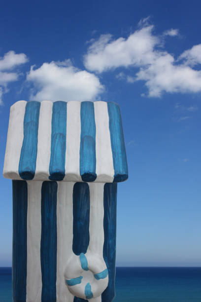 Bright blue and white striped beach umbrellas stand in a graphic row on the sand