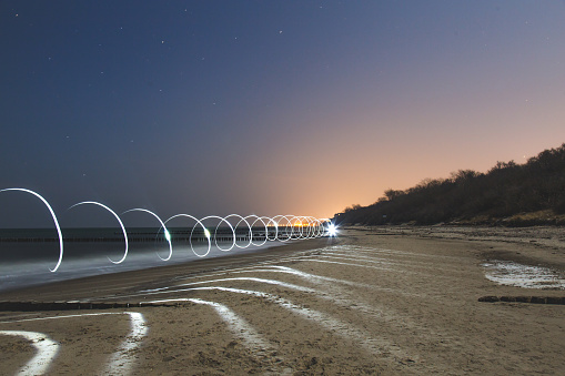 Kuhlungsborn beach in the Baltic sea at night. The light is from a technique light painting with 25 second exposure. Spiral shape should represent abstract tunnel or portal, teleport of some kind