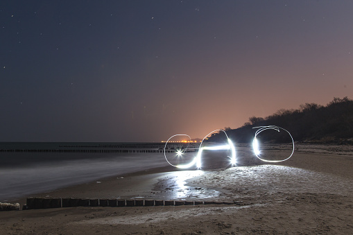 Kuhlungsborn beach in the Baltic sea at night. The light is from a technique light painting with 25 second exposure. Letters 