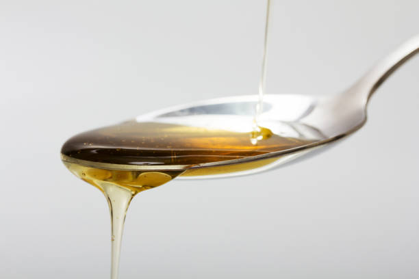 istock Honey pouring from spoon against a light background 647654118
