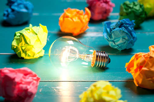Incandescent bulb and colorful notes on turquoise wooden table