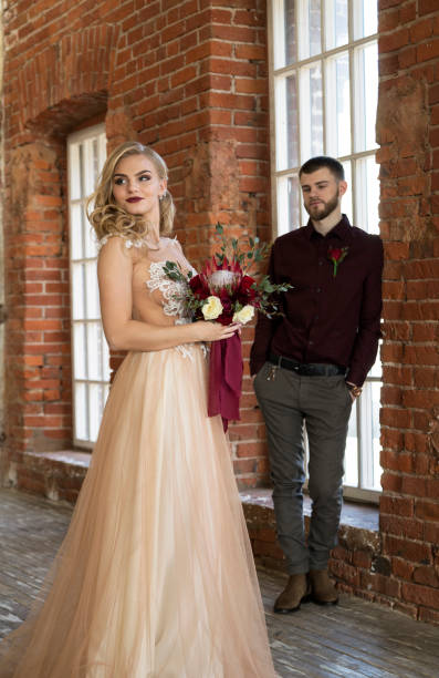 istock bride and groom posing in front of window 647660198