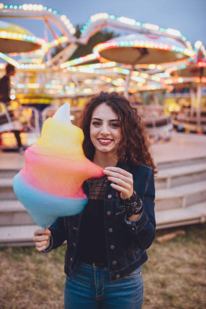 istock Beautiful brunette eating cotton candy, luna park 647660582