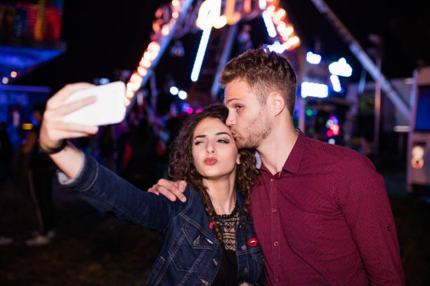 istock Young couple embracing in luna park, selfie 647664158