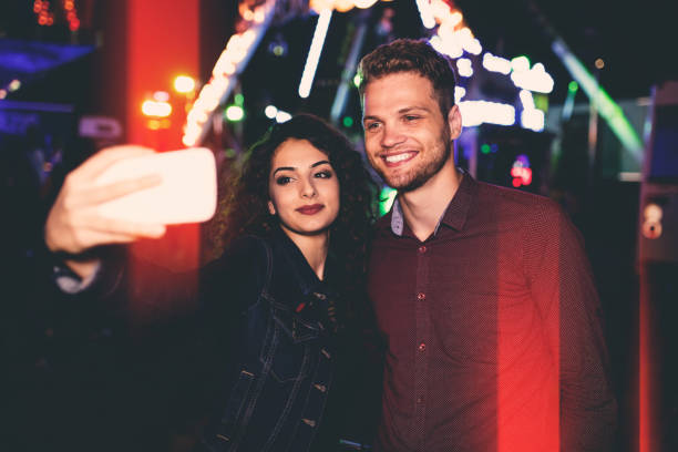 istock Young couple taking selfies in amusement park 647665160