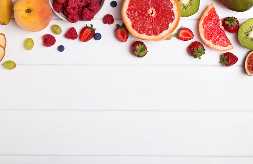 Fruits and berries on the white wooden background with negative space