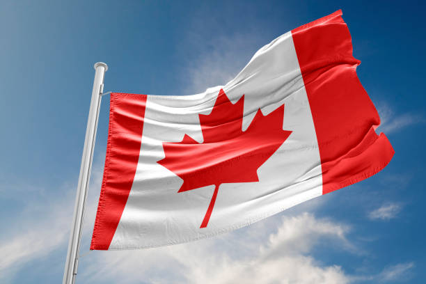 Canadian Flag is Waving Against Blue Sky Canadian flag is waving at a beautiful and peaceful sky in day time while sun is shining. canada flag blue sky clouds stock pictures, royalty-free photos & images