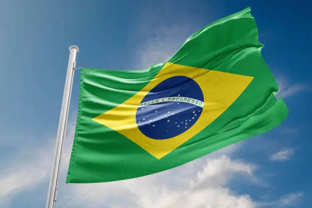 Brazilian flag is waving at a beautiful and peaceful sky in day time while sun is shining.