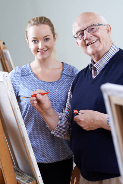 istock Senior Man Attending Painting Class With Teacher 647695680