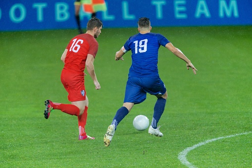 Football players challenging for ball on field during match.