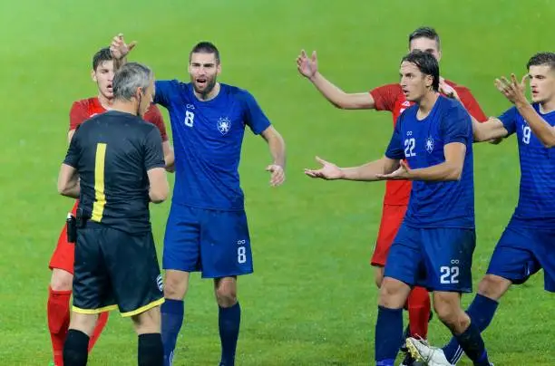 Football players appeal for an yellow card during match.