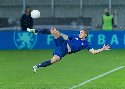 Football player kicking ball in mid-air.