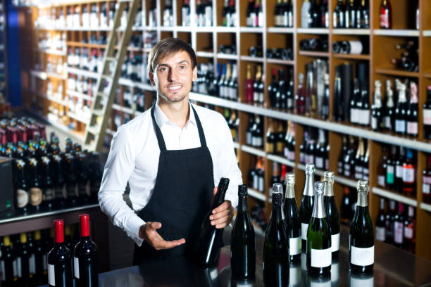 istock Man seller wearing uniform having bottle of wine 647704228