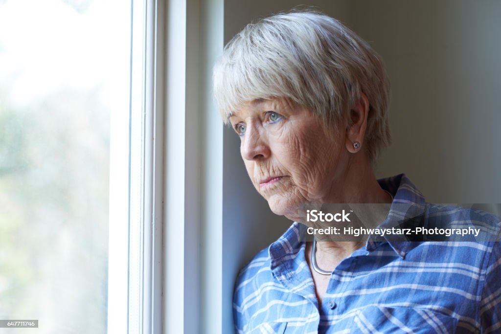 Senior mujer que sufría de depresión fuera de ventana - Foto de stock de Tercera edad libre de derechos
