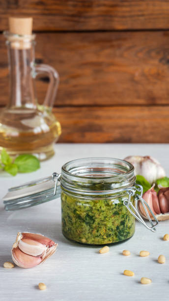 istock Glass jar of pesto sauce on white kitchen table. 647714352
