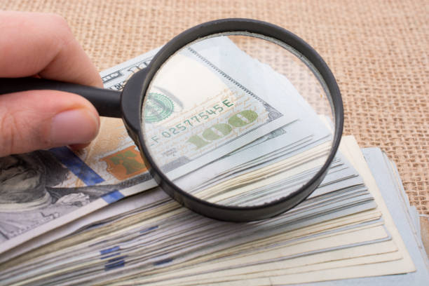 istock Magnifying glass over the banknote bundle of US dollar 647719748