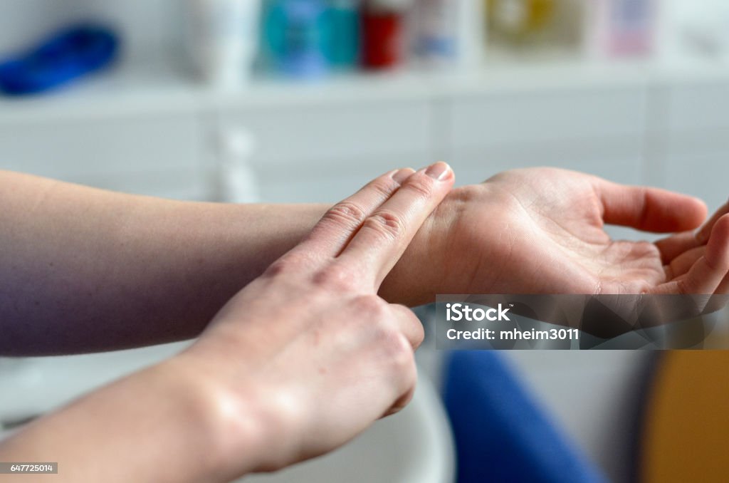 Hands of a woman checking her pulse Hands of a woman checking her pulse with two fingers, medical concept Taking Pulse Stock Photo