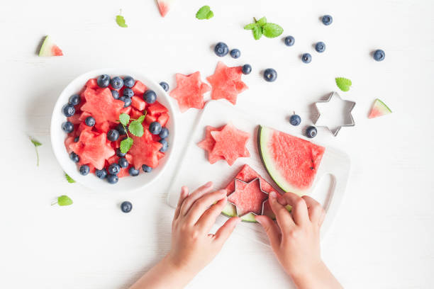 istock Watermelon salad. Children's hands cooking fruit salad on white table 647728656