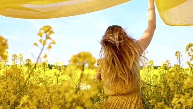 SLO MO Woman running with a shawl among canola flowers