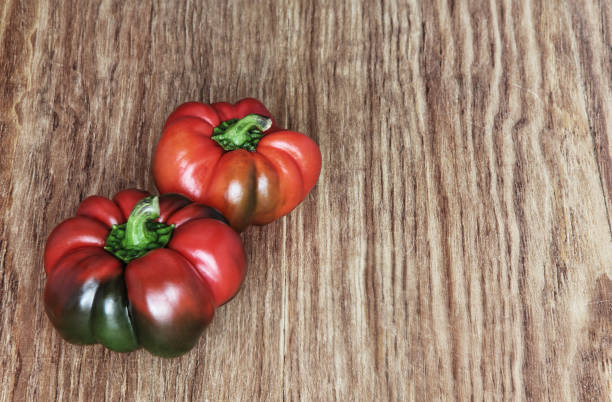 istock Two red sweet pepper on brown wooden background. 647732202