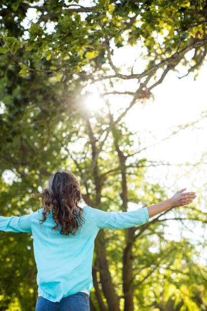 istock Woman standing with arms outstretched in park 647735284