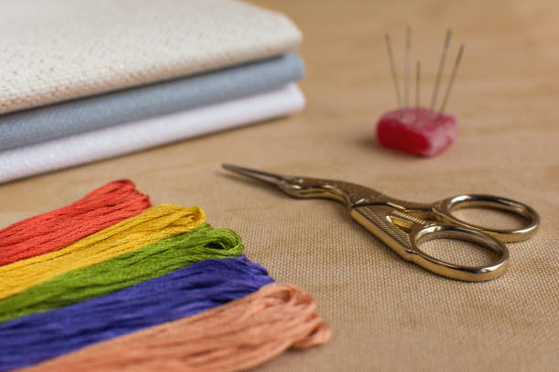 istock Cross-stitch kit for embroidery consisting of scissors, needles, multicoloured threads and canvas. Focus on the scissors. 647735344