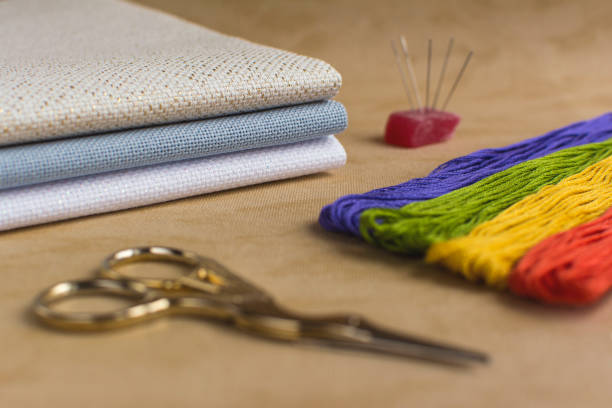 Cross-stitch set for embroidery consisting of needles, colourful threads, canvas and scissors. Focus on the sheets of canvas.