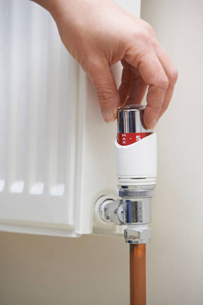 istock Close Up Of Hand Adjusting Heating Thermostat 647753550