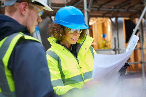 female construction foreman instructing a worker . - architect construction hardhat planning imagens e fotografias de stock