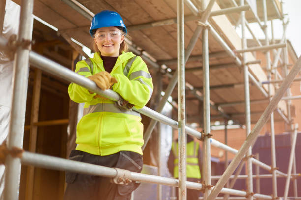 female construction worker portrait a female construction worker stands behind a scaffold and smiles to camera on a building site scaffolding stock pictures, royalty-free photos & images