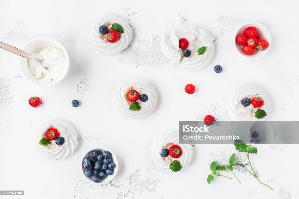 Meringues Pavlova cakes with strawberry and blueberry Meringues Pavlova cakes with strawberry and blueberry. Flat lay, top view Pavlova - Dessert Stock Photo