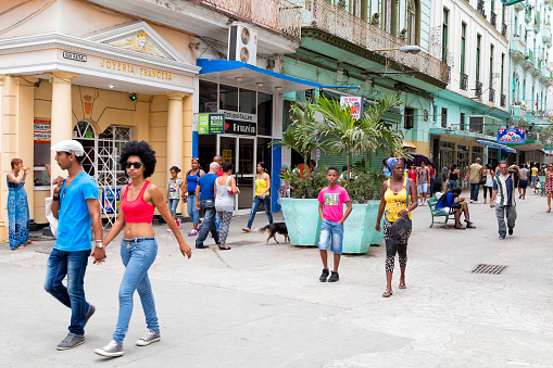 Pedestrians, shopppers, tourists walking down shopping street on a sunny day in Havana Vieja, Cuba