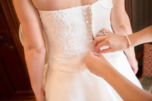 istock Bridesmaid is helping the bride to buttoning wedding dress 647786178