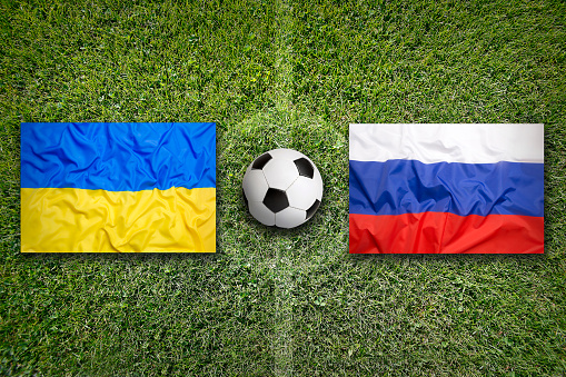 Ukraine vs. Russia flags on green soccer field