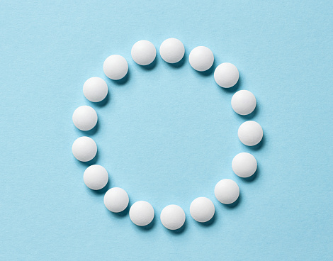 white pills on blue background, top view